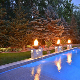 Fire pits surrounding an inground pool in a back yard with pine trees