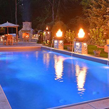 Backyard pool with waterfalls and lit stone torches