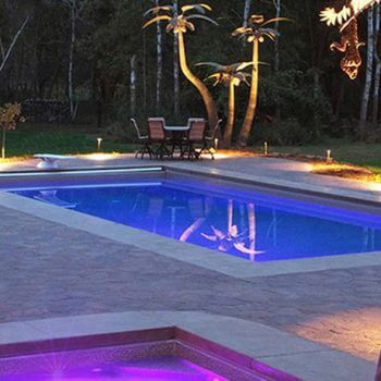 pool and hot tub lit up with purple and blue lights at dusk